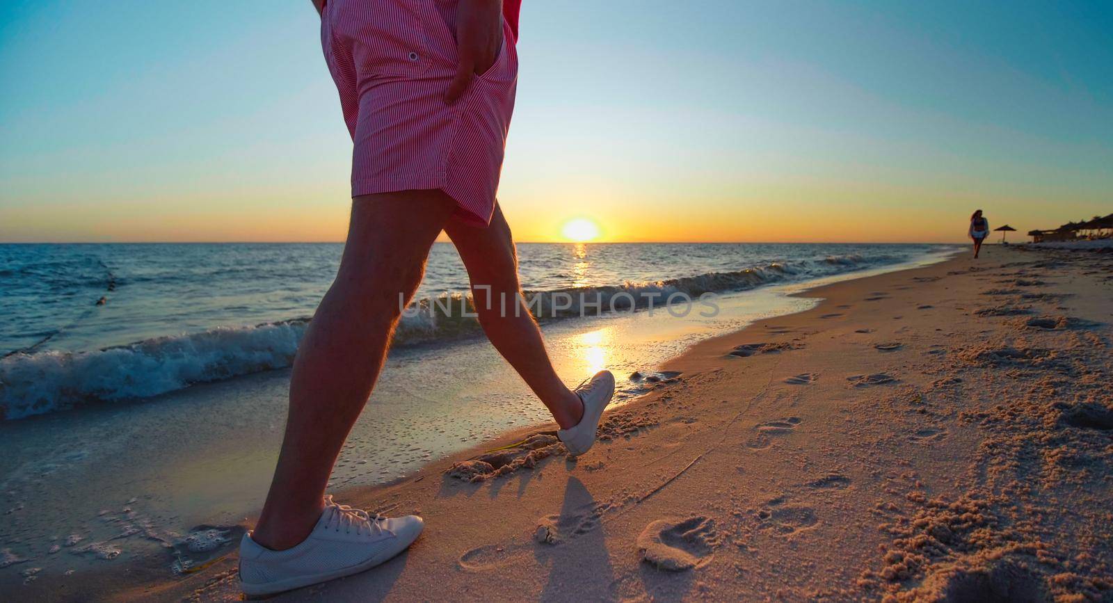 Man walking on the beach at the sunset. People enjoying life, exotic holiday vacation, holiday destination at the sea. Luxury summer beach resort. Beautiful seaside in Tunisia, Africa.