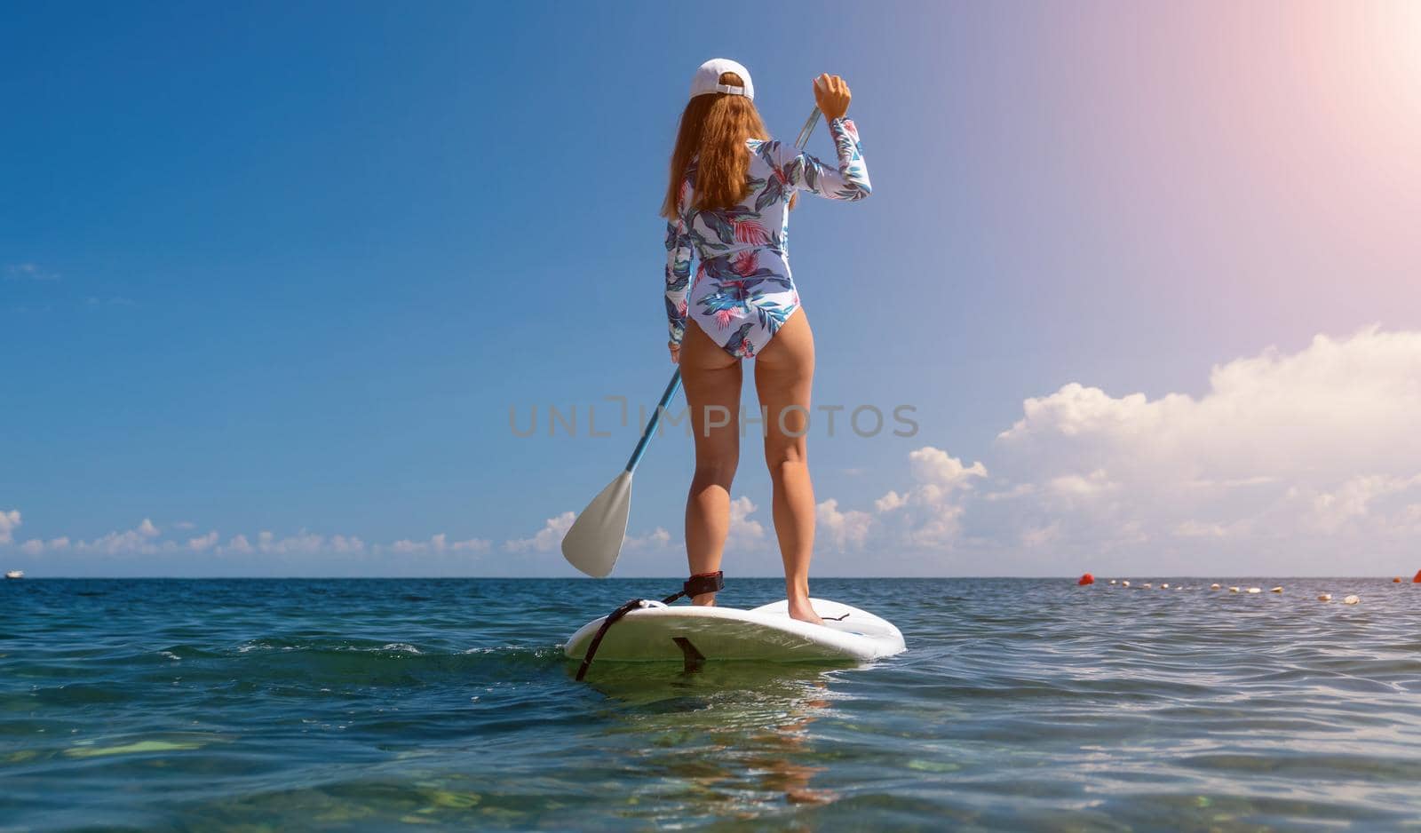 SUP Stand up paddle board. Young woman sailing on beautiful calm sea with crystal clear water. The concept of an summer holidays vacation travel, relax, active and healthy life in harmony with nature