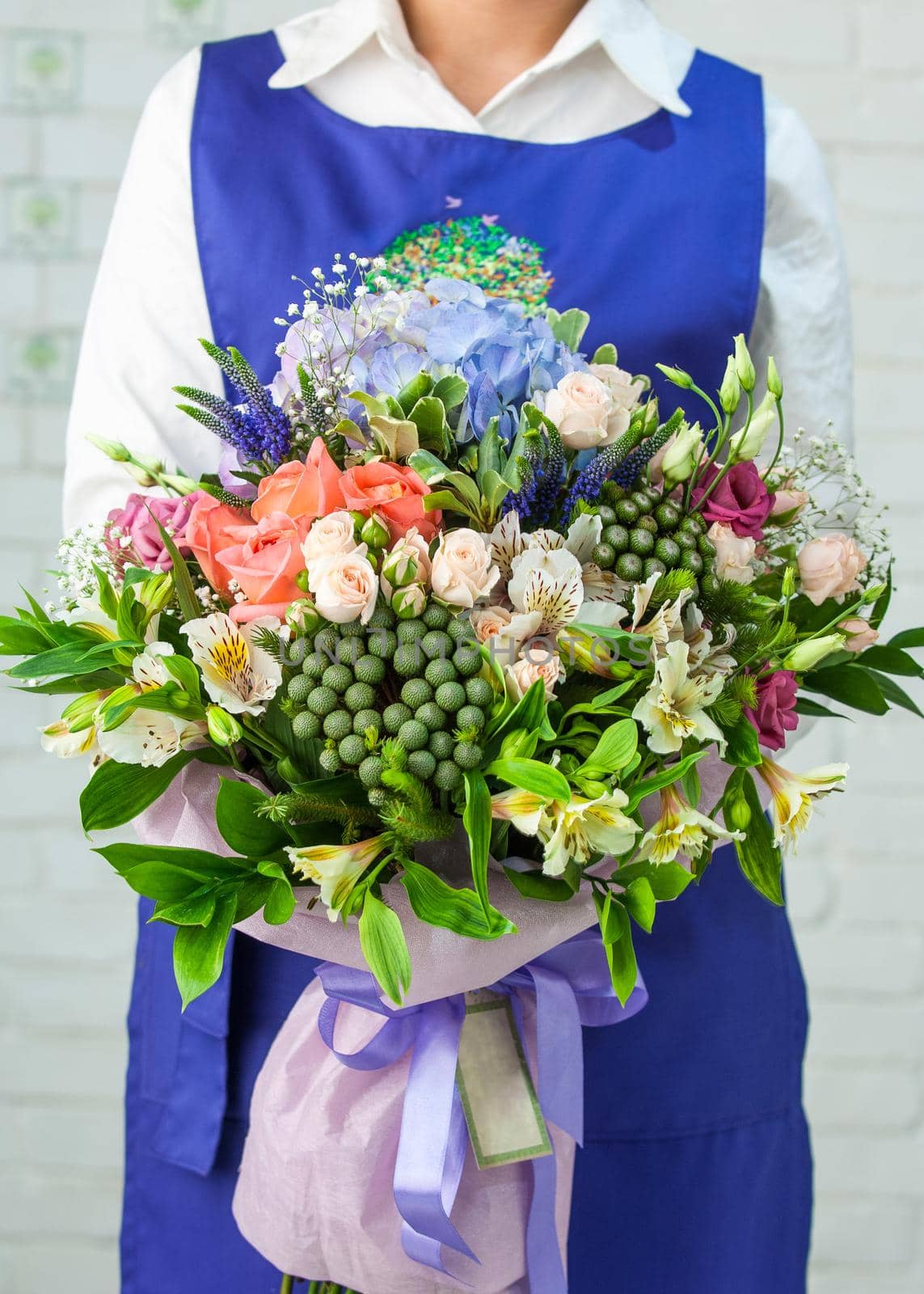 A woman holding a beautiful bouquet with roses, lisianthus, alstroemeria, and hortensia