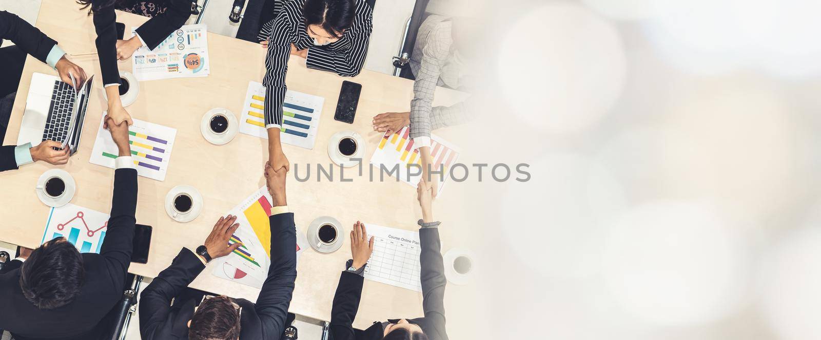 Group business people handshake at meeting table in office together with confident shot from top view . Young businessman and businesswoman workers express agreement of investment deal. broaden view