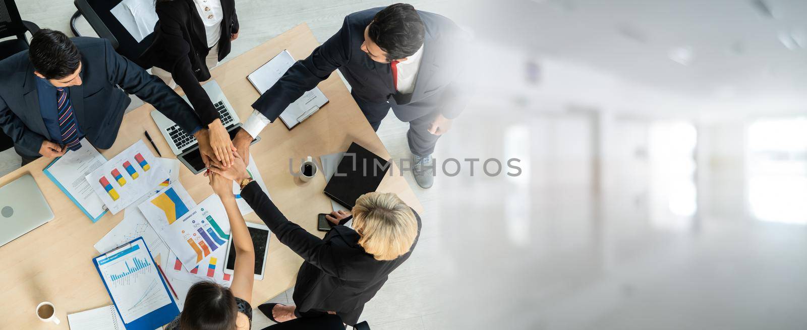 Happy business people celebrate teamwork success in widen view together with joy at office table shot from top view . Young businessman and businesswoman workers express cheerful victory .