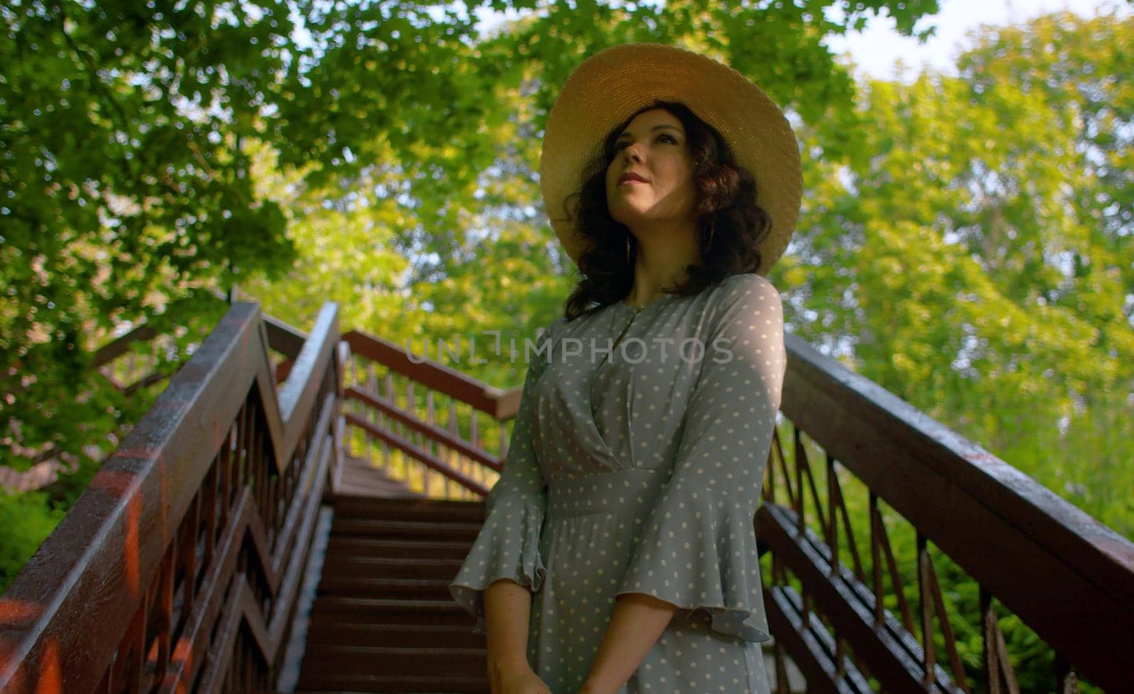 Beautiful woman in a straw hat and old fashion dress posing on the stairs