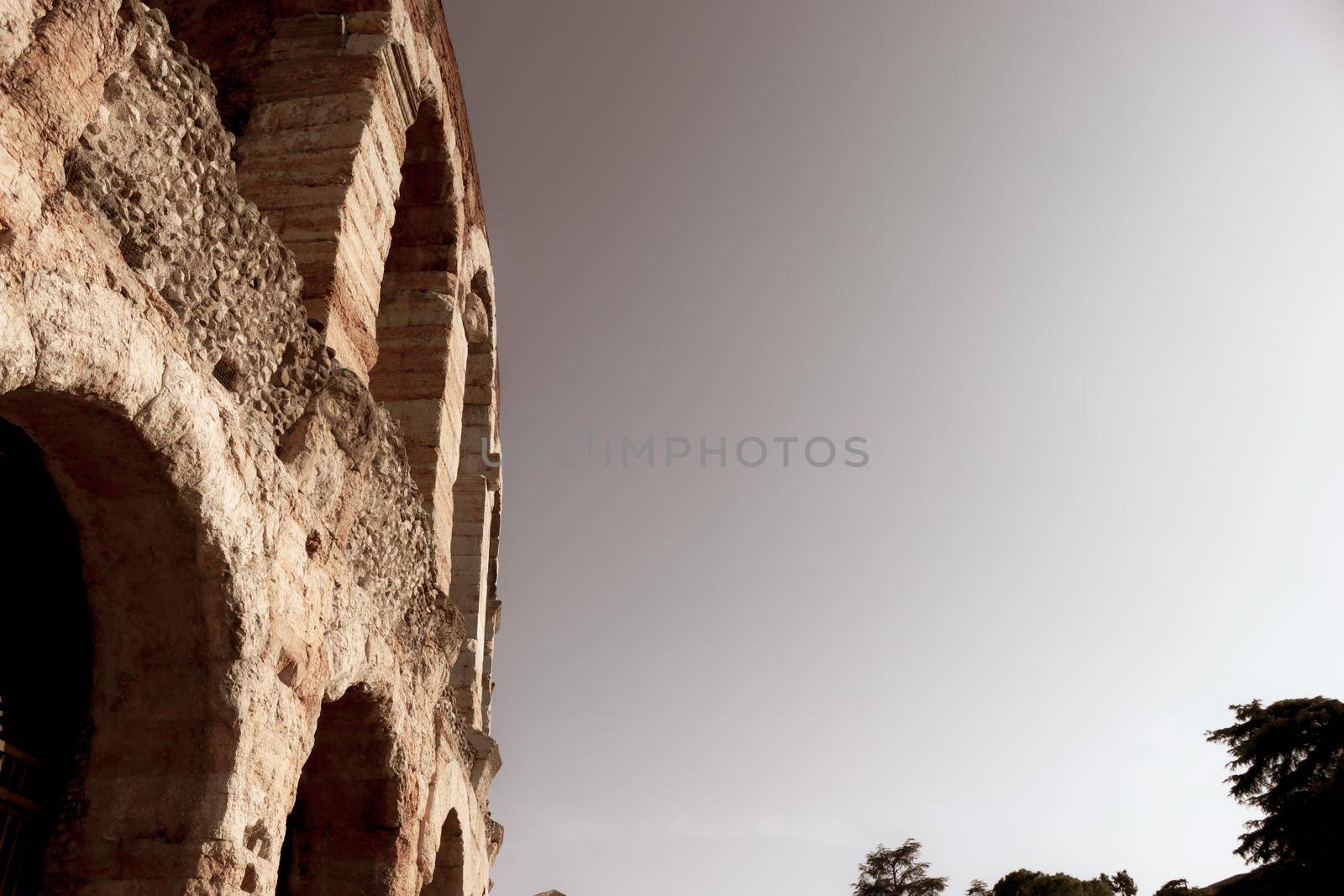 ROME, ITALY - February 05, 2022: Panoramic view around the Colosseum in city of Rome, Italy. Cold and gray sky in the background. Macro photography of the green parks with the old buildings.