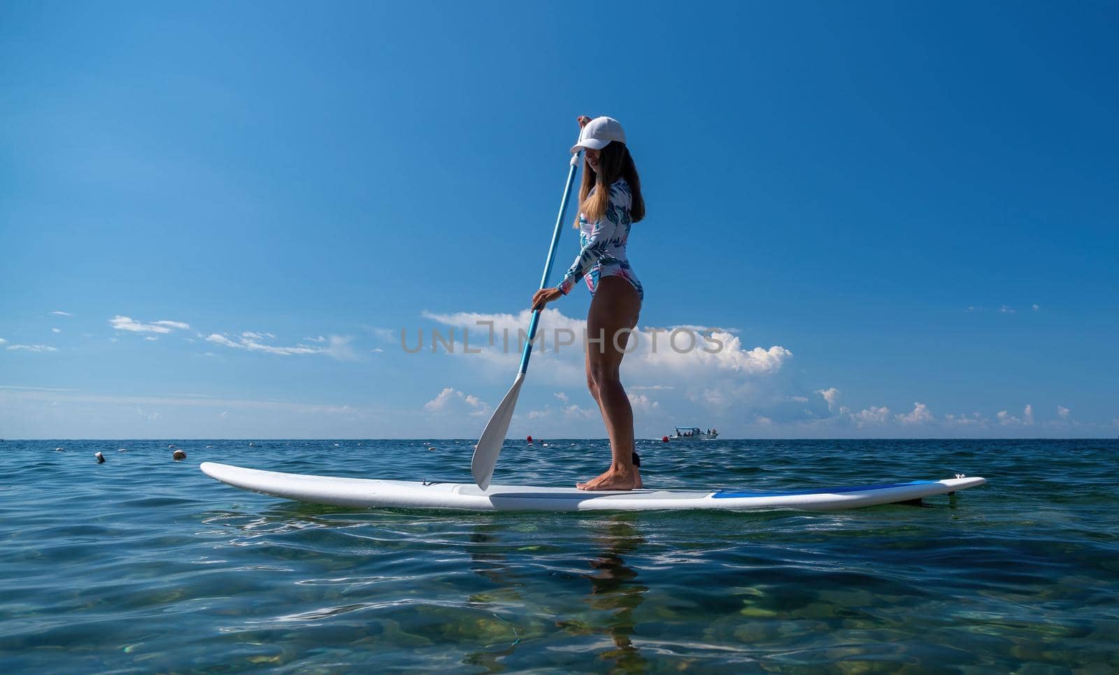 SUP Stand up paddle board. Young woman sailing on beautiful calm sea with crystal clear water. The concept of an summer holidays vacation travel, relax, active and healthy life in harmony with nature