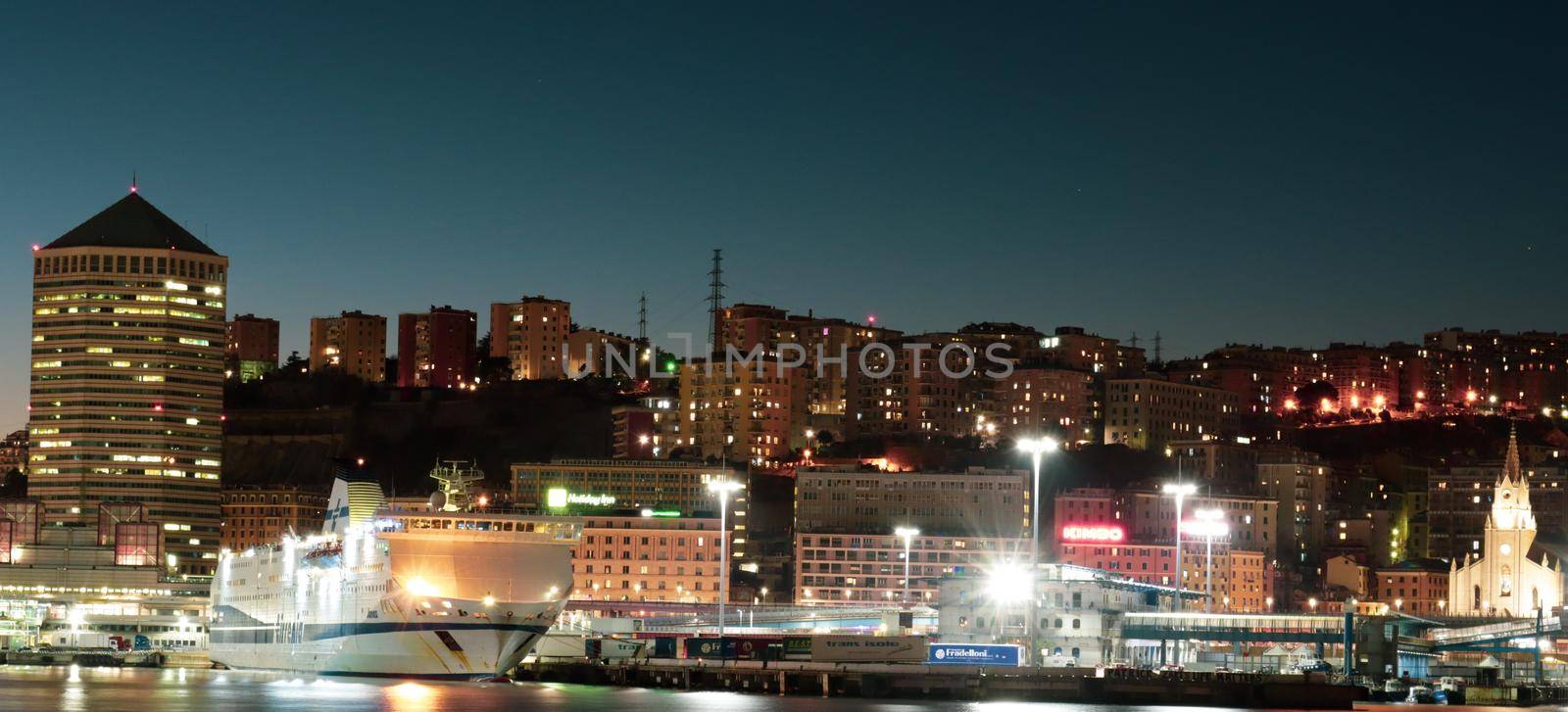 Genova, Italy - July 02, 2022: View of the city and the old harbor (Porto Antico) by night. City lights reflection over the water.