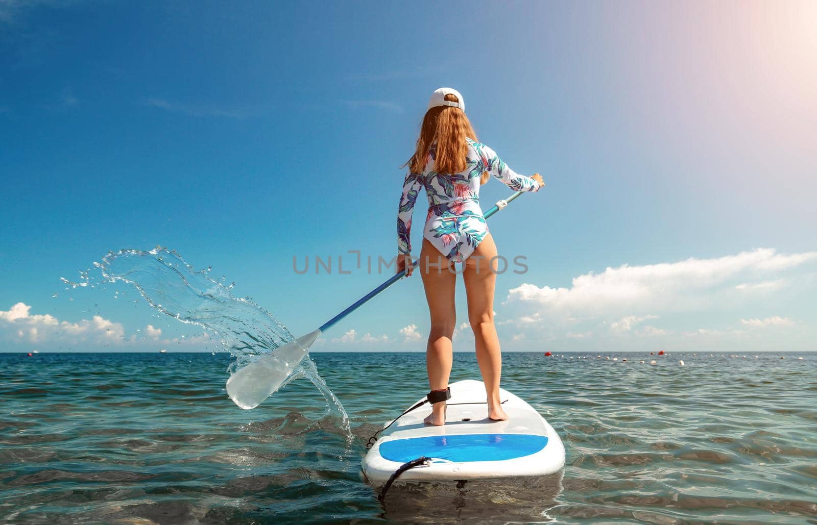 SUP Stand up paddle board. Young woman sailing on beautiful calm sea with crystal clear water. The concept of an summer holidays vacation travel, relax, active and healthy life in harmony with nature