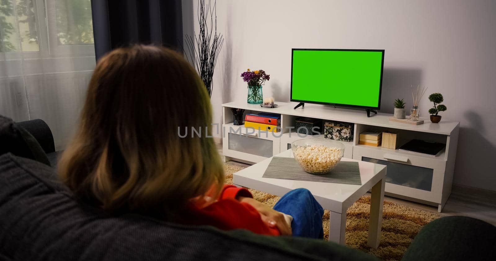 Girl Watching Green Chroma Key Screen TV, Relaxing Sitting on a Couch Home. Woman in living room Watching Sports Match, News, Sitcom TV Show or a Movie on Green Screen.