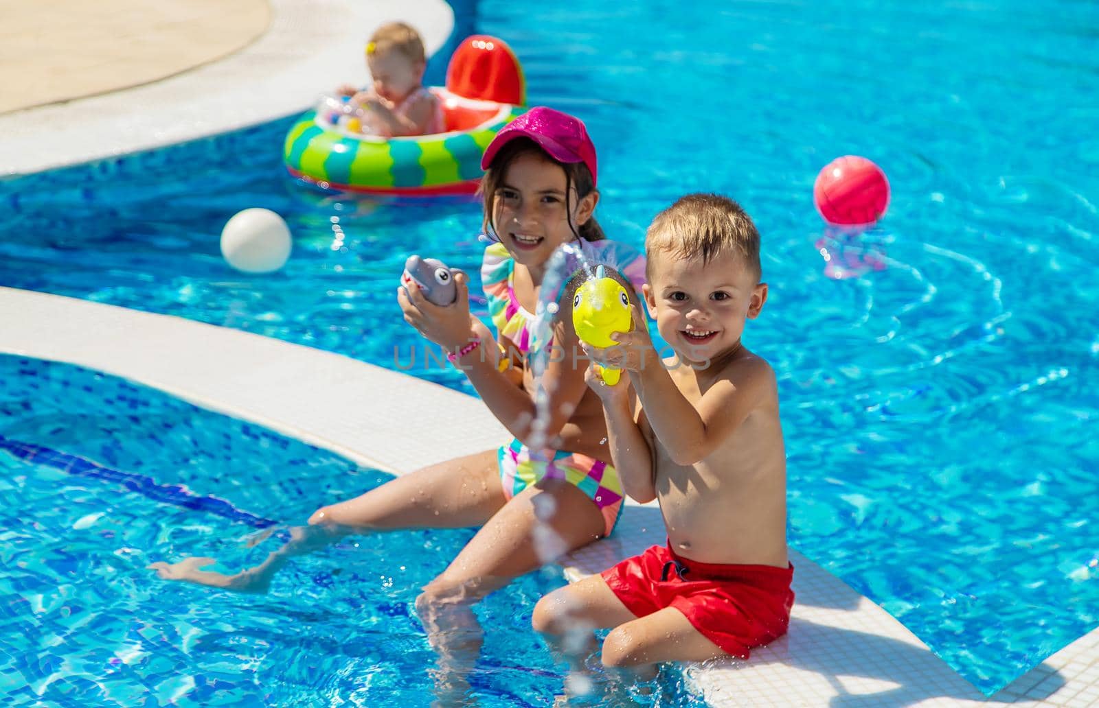 Children play with water pistols in the pool. Selective focus. Water.