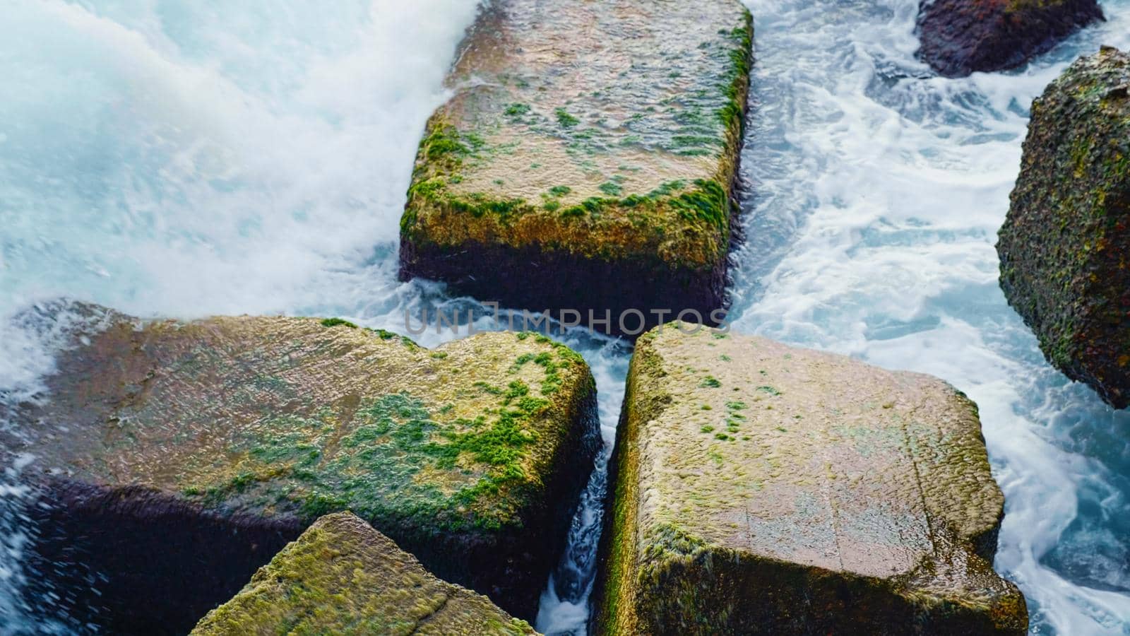 Close up stormy and foamy waves breaking stones