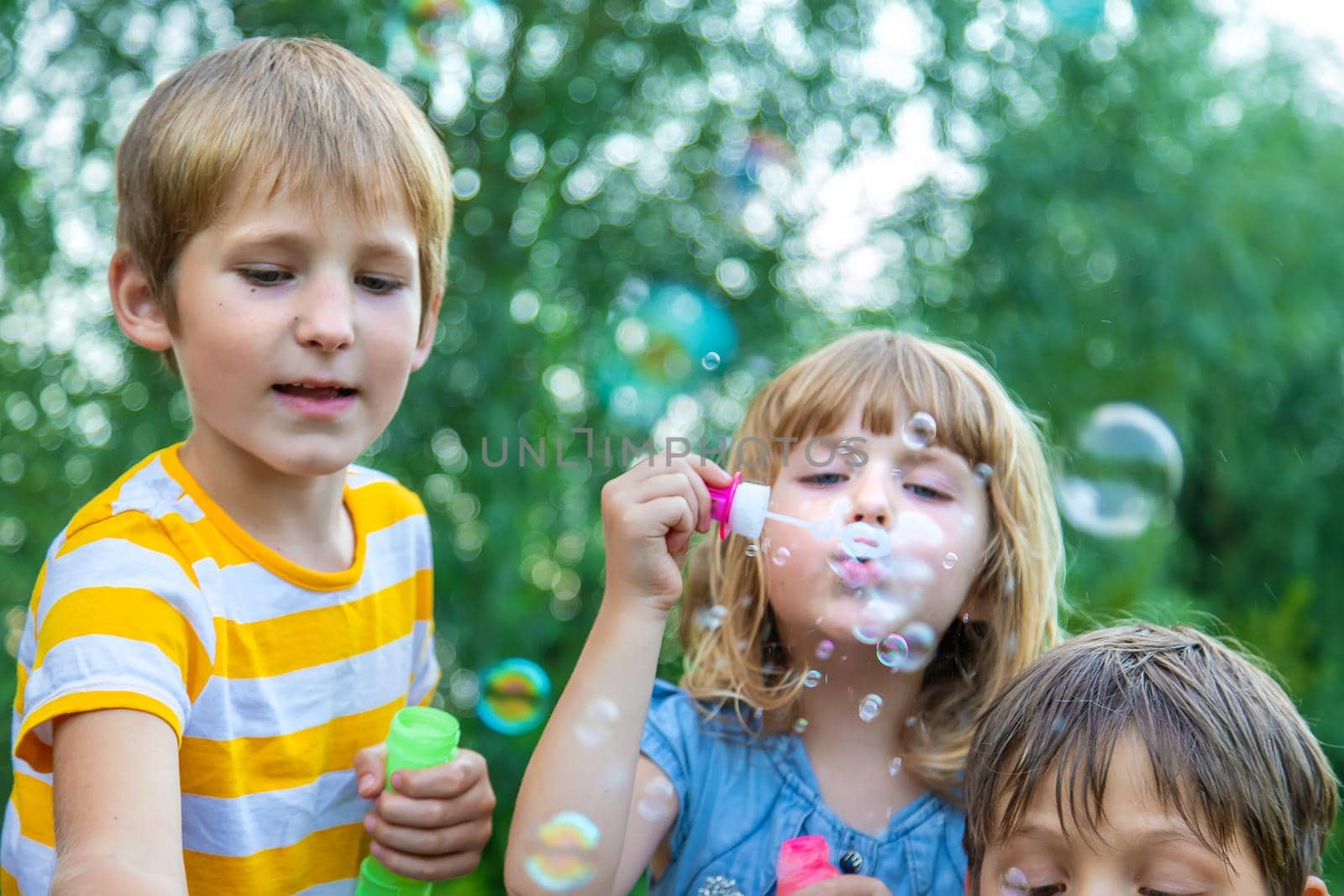 Children blow bubbles in the street. Selective focus. by yanadjana