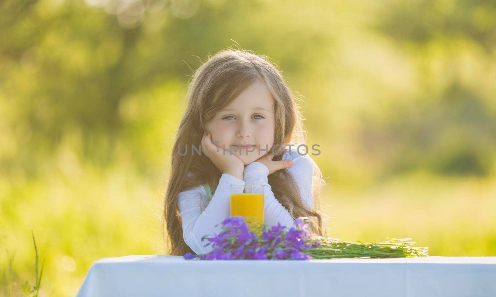 little girl in nature with a glass of orange juice