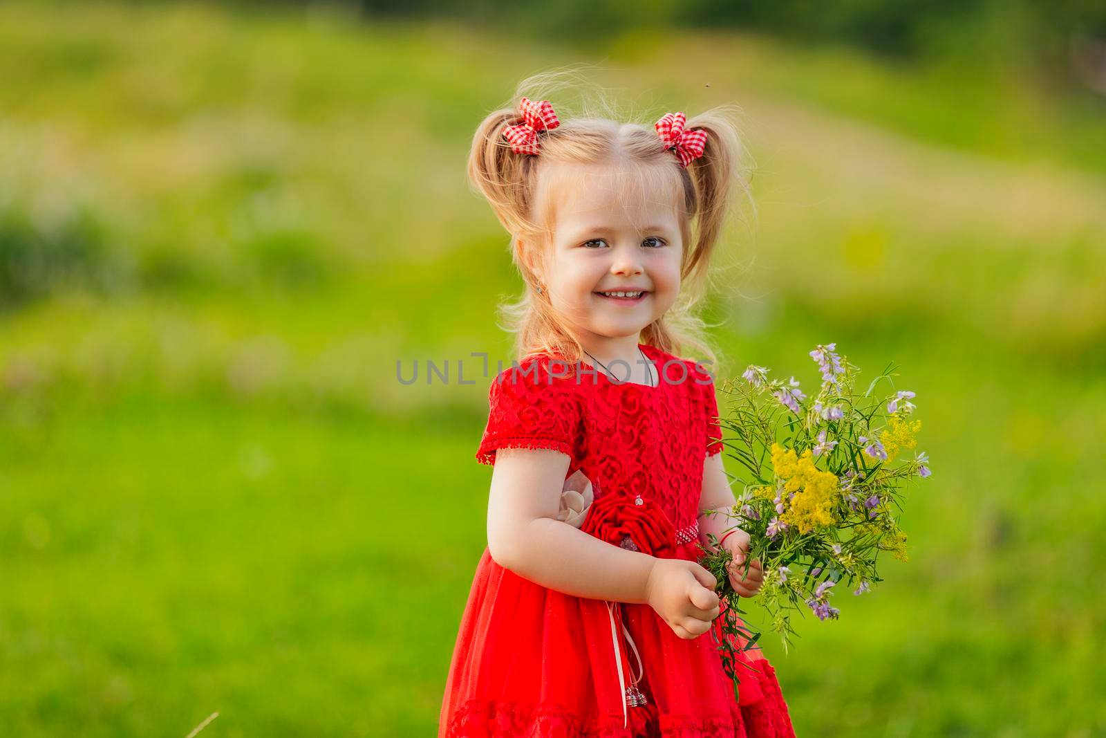 girl in a red dress and with a bouquet of wild flowers on the lawn