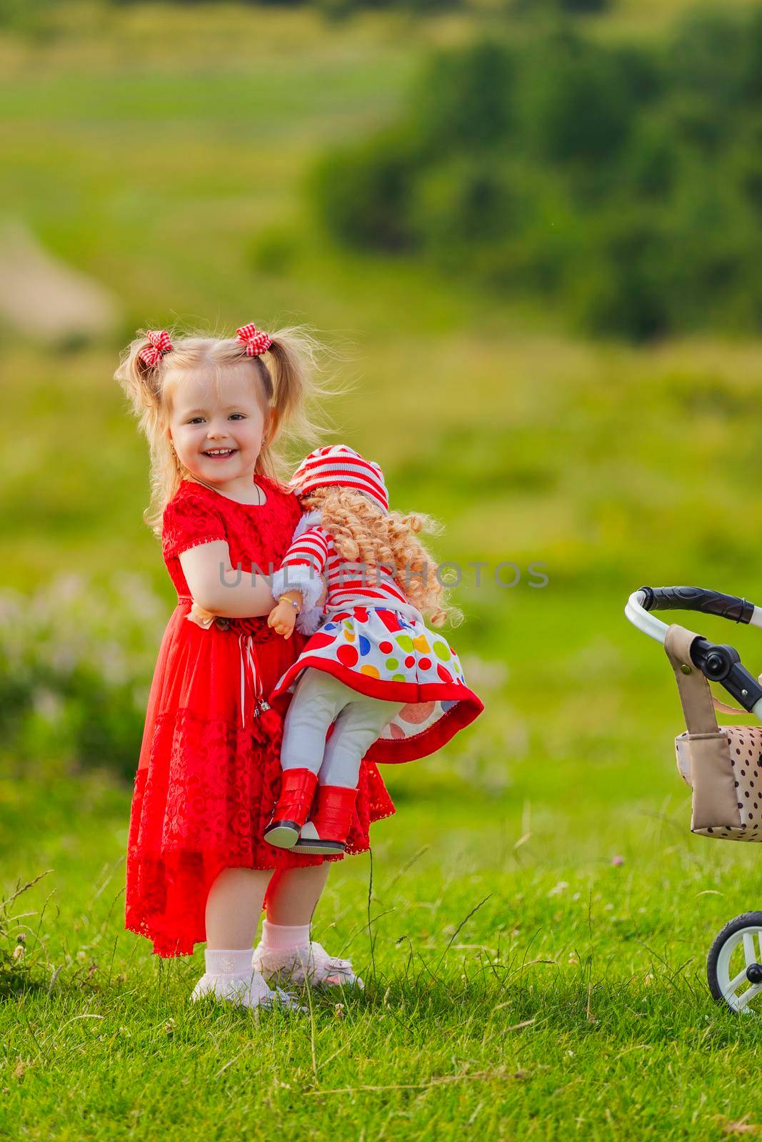 girl with a doll in her hands stands in nature by zokov