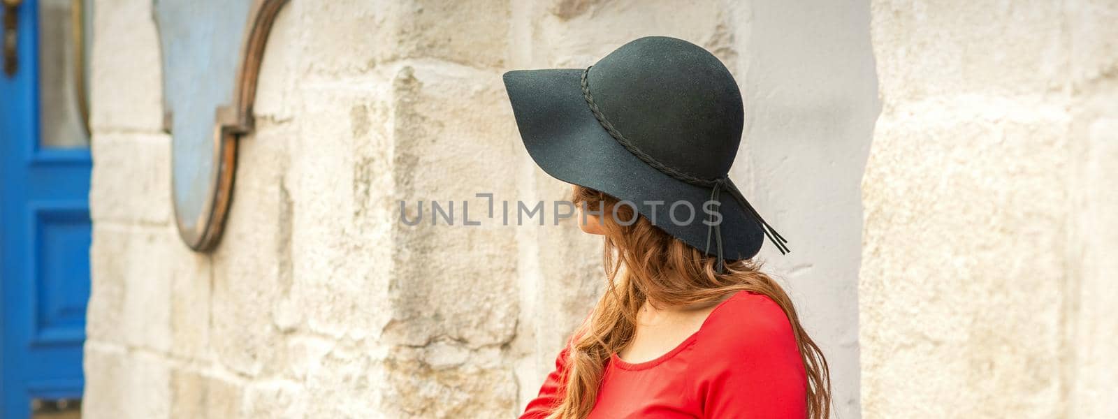 Beautiful young caucasian woman wearing black hat and red dress
