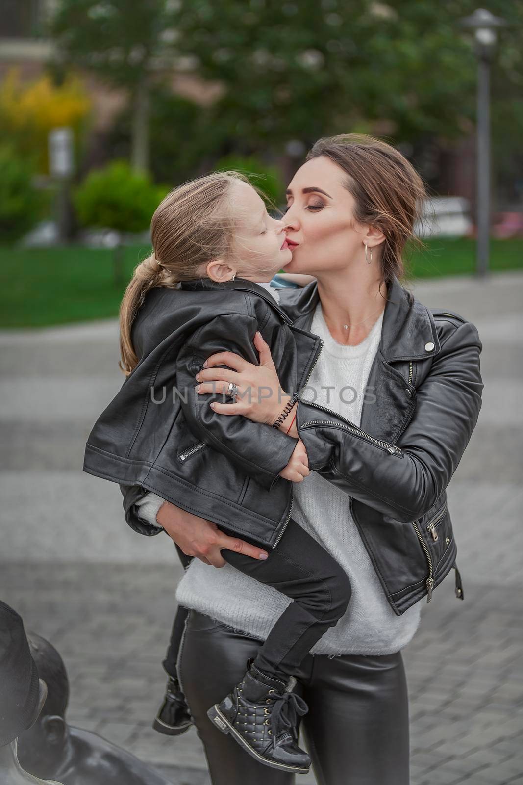 Mom carries her daughter in her arms while walking in the city