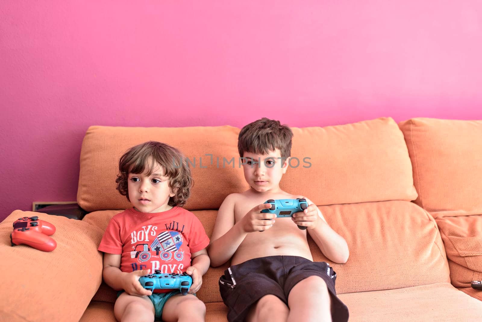Computer game competition. Gaming concept. Excited children leaning on the sofa back playing video game with joysticks. by jbruiz78