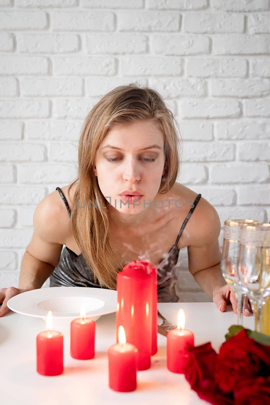 Romantic date, young woman blowing out candle on romantic date table