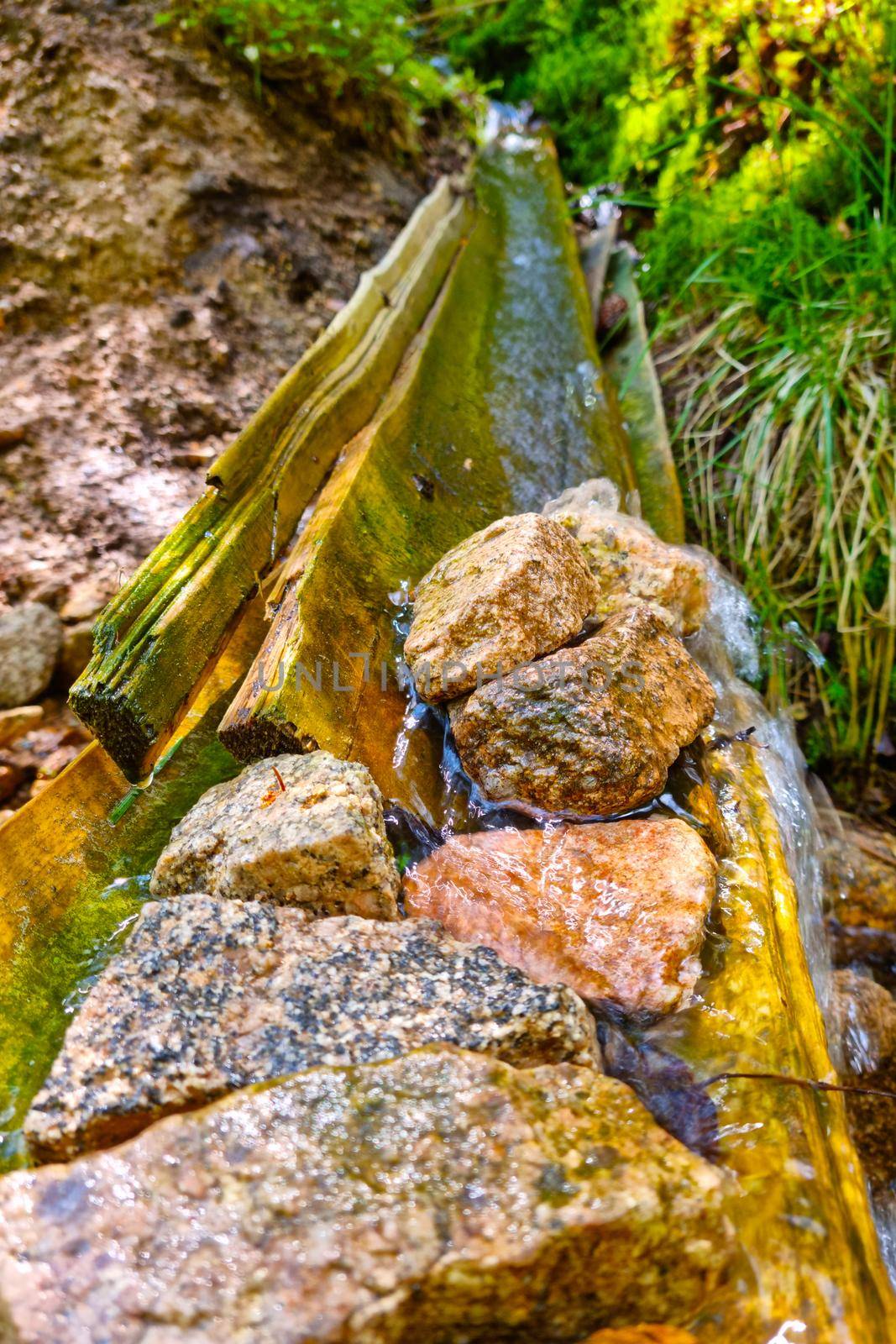 Clean cold water flows down a wooden gutter. by kip02kas