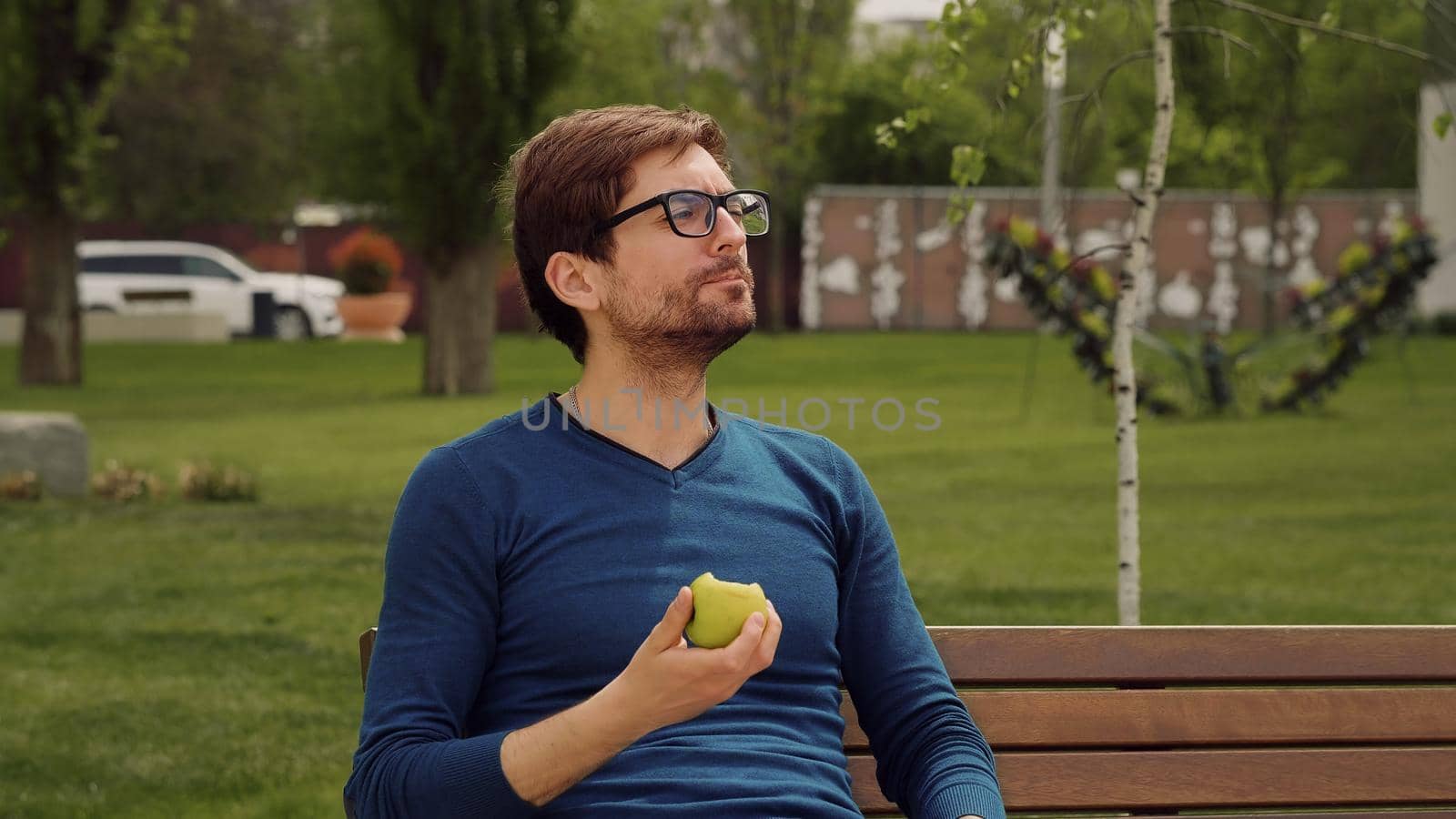 Handsome Man Eating Heathy food. Eating a apple as snack. Enjoying an fruit. Male Portrait have snack in park.