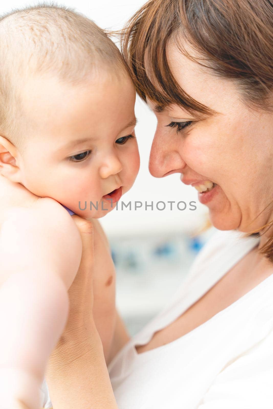 Young mother hugging her little son, sitting near the window and smiling. high quality photo