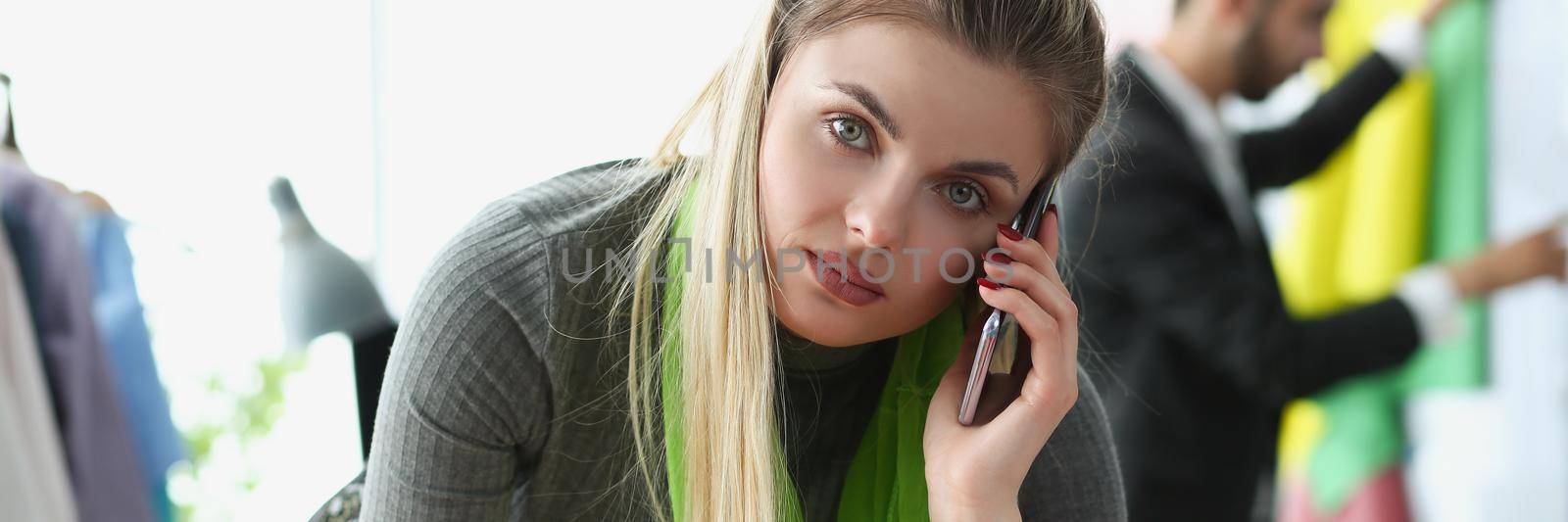 Blonde creative woman take order on phone for new clothes from client by kuprevich