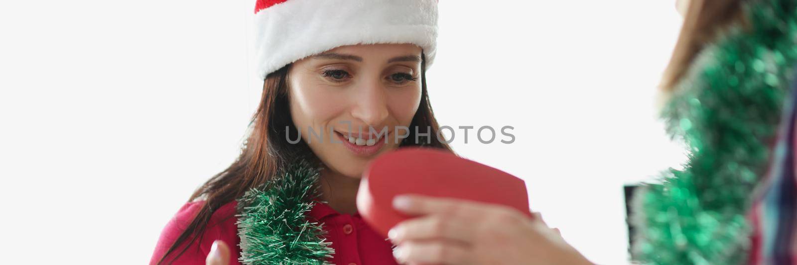 Portrait of woman giving present to best friend in beautiful red box. Festive mood and christmas outfit, ready to celebrate new year. Holiday, gift concept