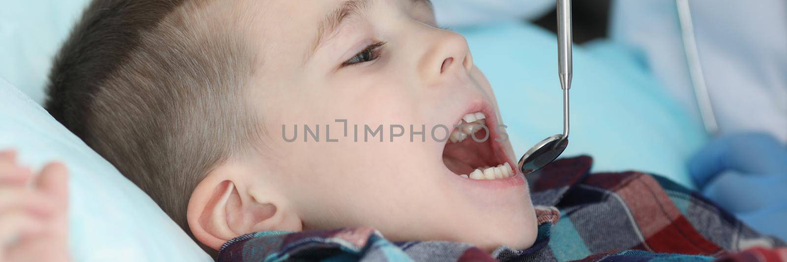 Portrait of pediatrician check kids health condition using special tool for mouth. Qualified family doctor provide diagnostic in clinic. Medicine concept