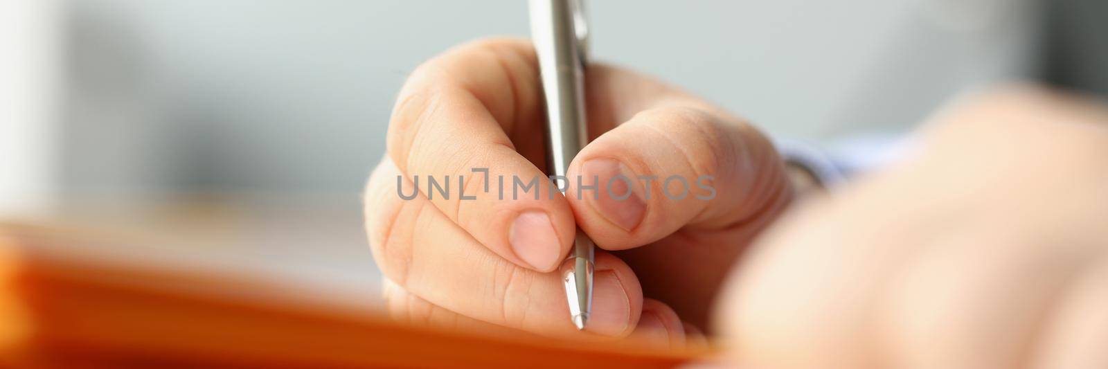 Close-up of professional businessman writing his idea in notebook with silver pen. Make plan for whole week in personal diary. Planning, compose concept