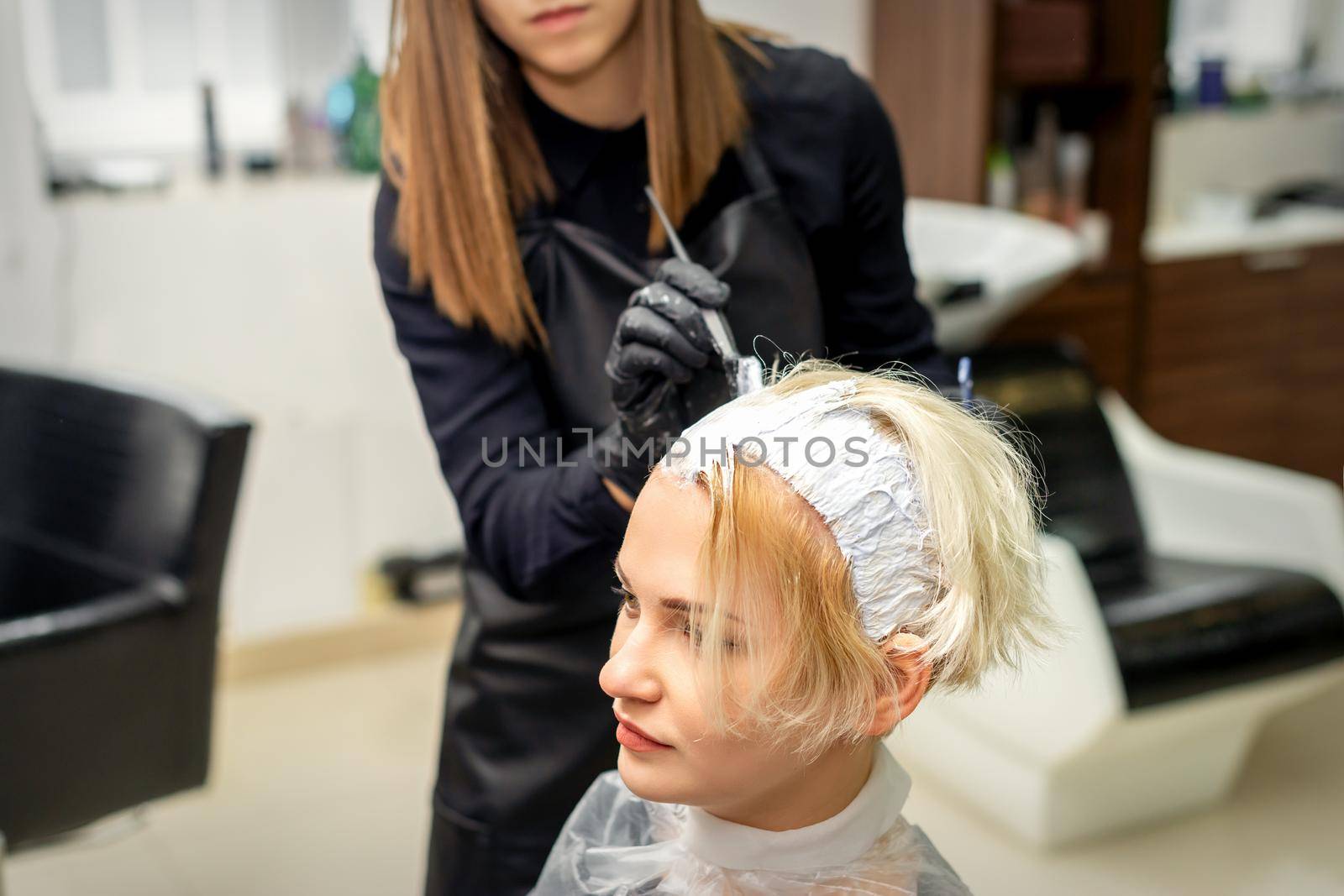 Stylist applies white dye to hair by okskukuruza