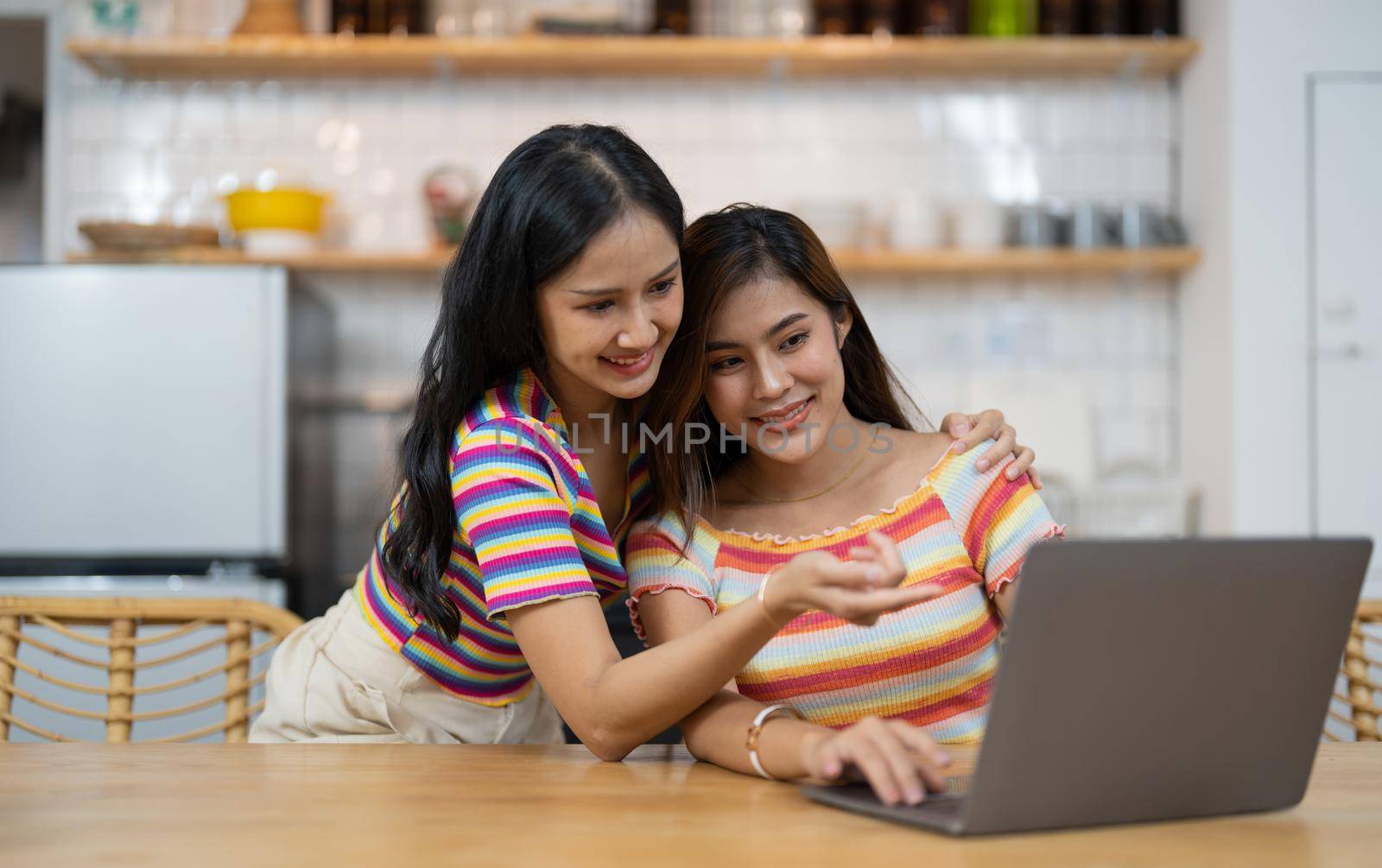Happy lesbian lgbtq couple in love cuddling, laughing having fun at home. Two diverse pretty affectionate women hugging, bonding. Lgbt relationship concept.