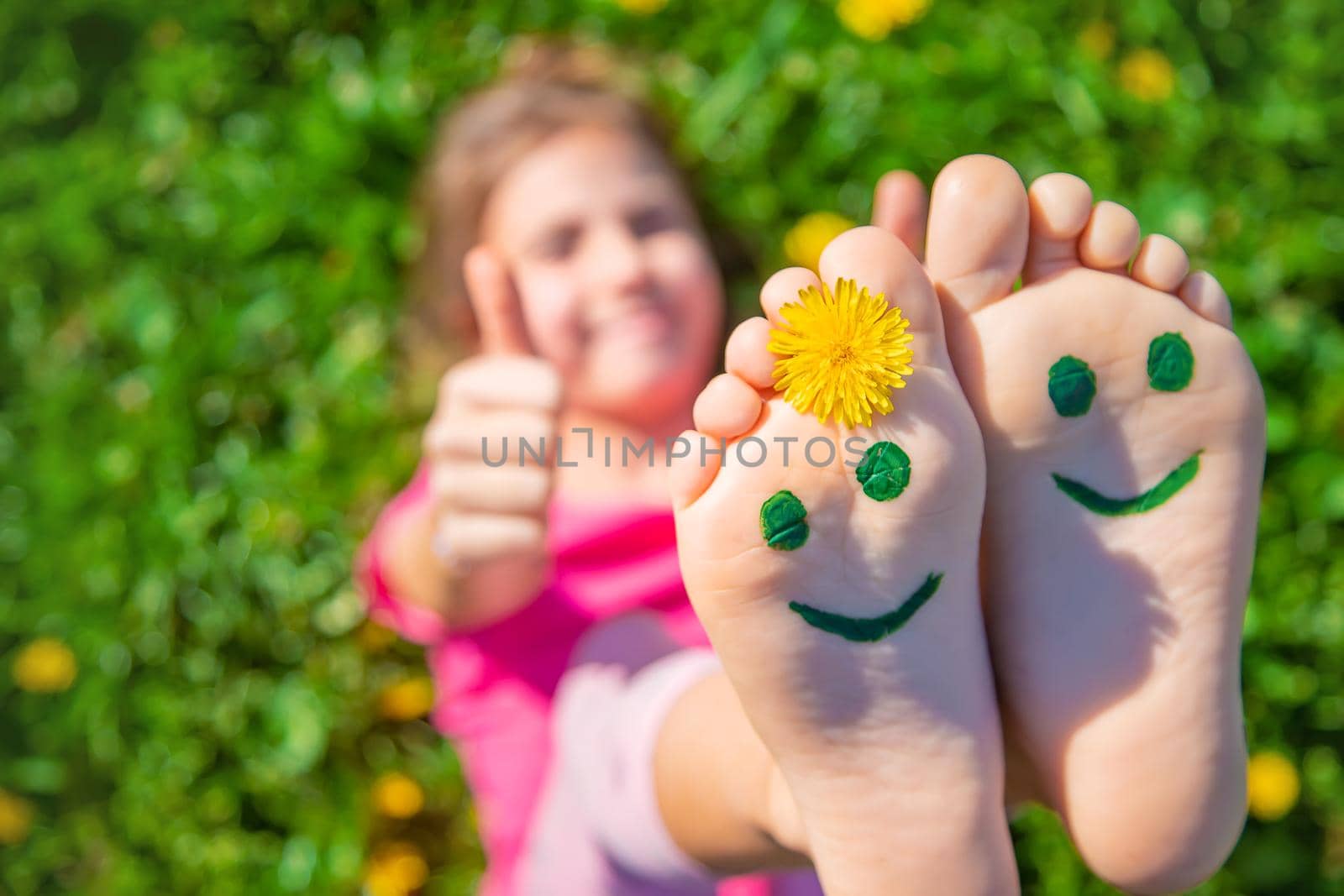 Child feet on the grass drawing a smile. Selective focus. Kid.