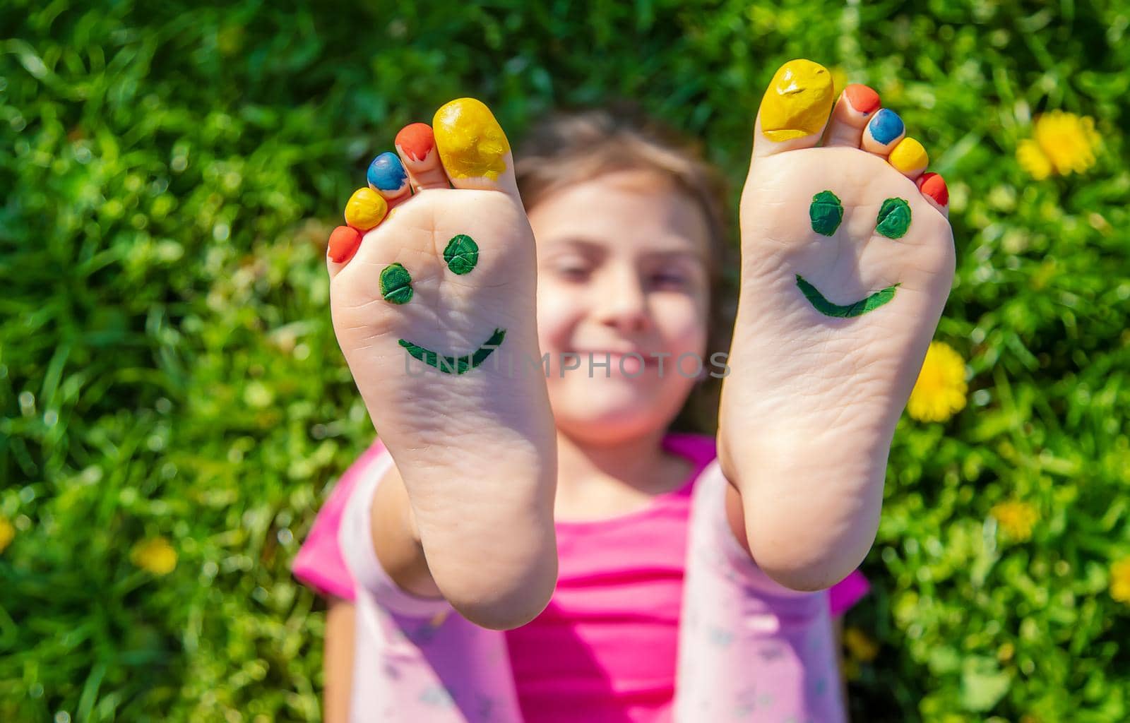 Child feet on the grass drawing a smile. Selective focus. by yanadjana