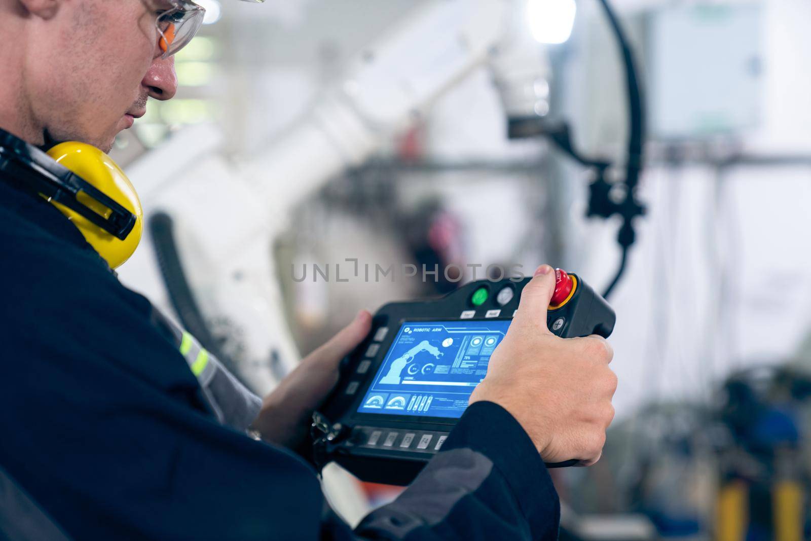 Young factory worker working with adept robotic arm in a workshop . Industry robot programming software for automated manufacturing technology .