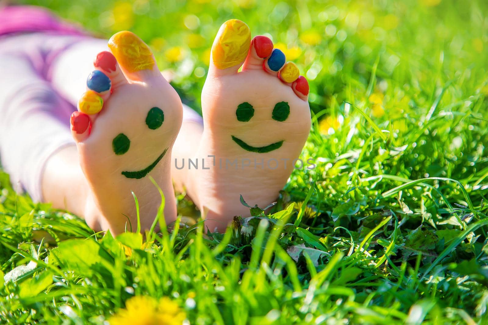 Child feet on the grass drawing a smile. Selective focus. by yanadjana