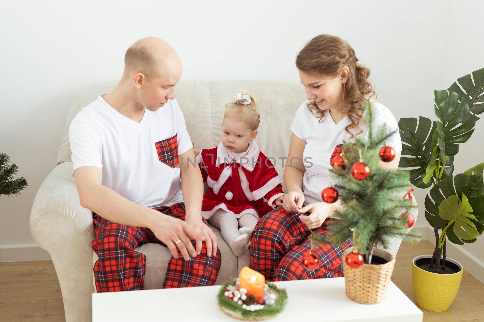 Baby child with hearing aid and cochlear implant having fun with parents in christmas room. Deaf , diversity and health concept by Satura86