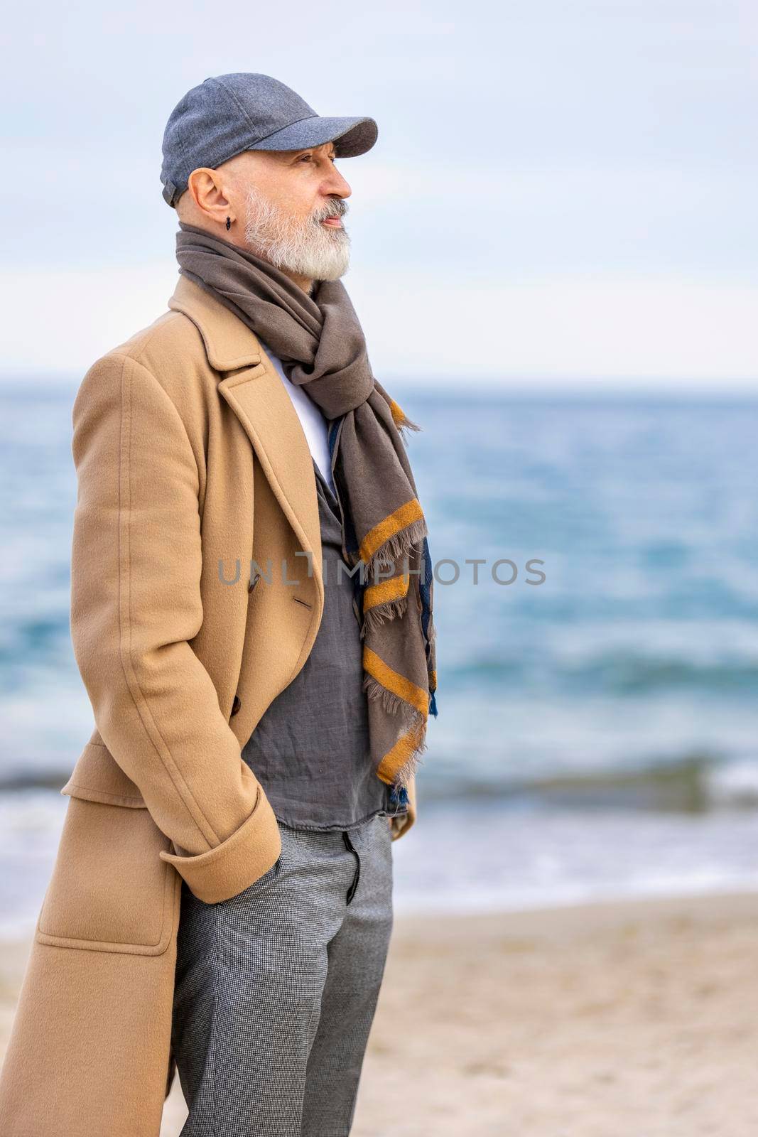 an aged man walking along the beach against the background of the sea