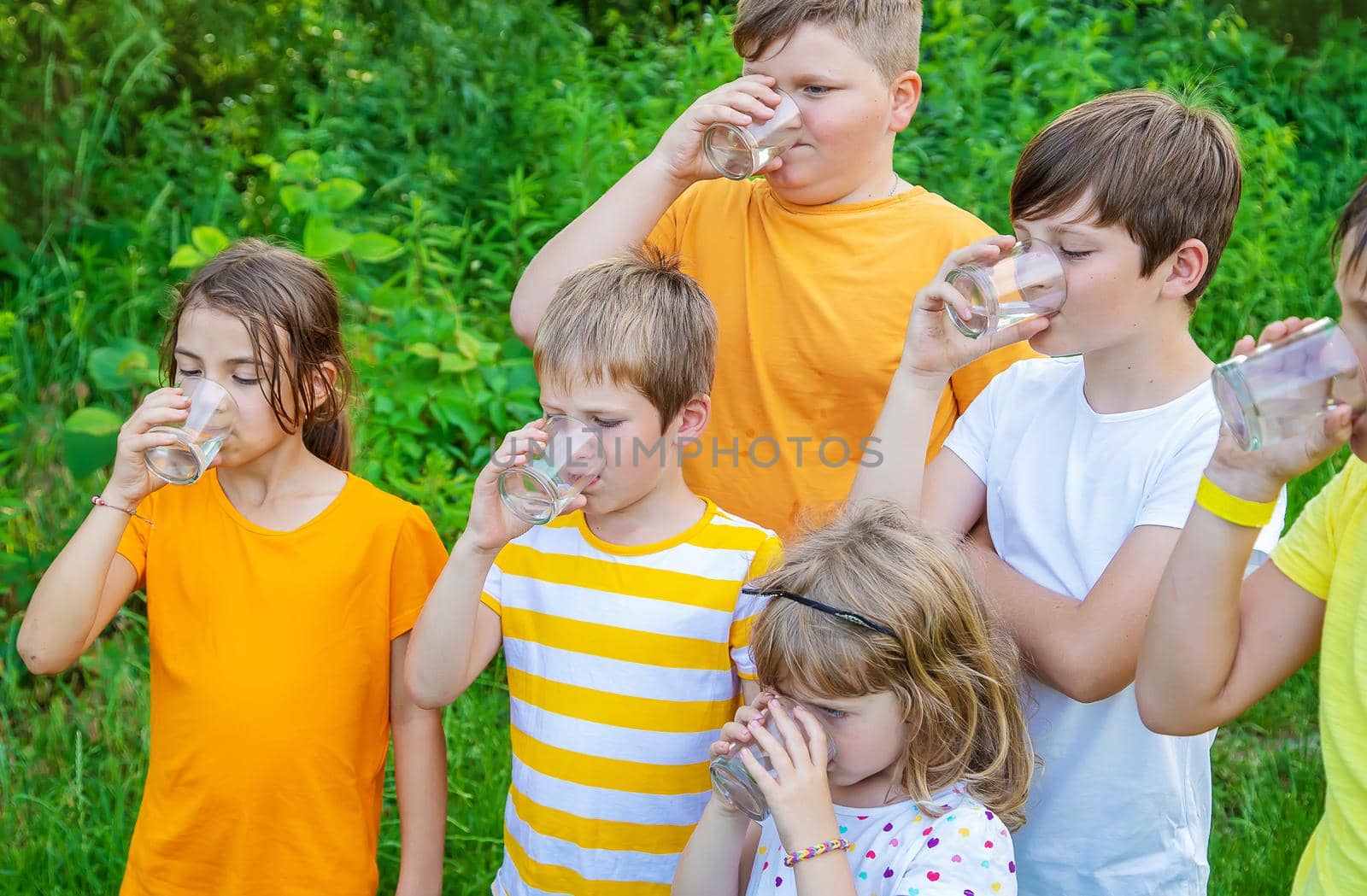 Children drink water outside together. Selective focus. by yanadjana