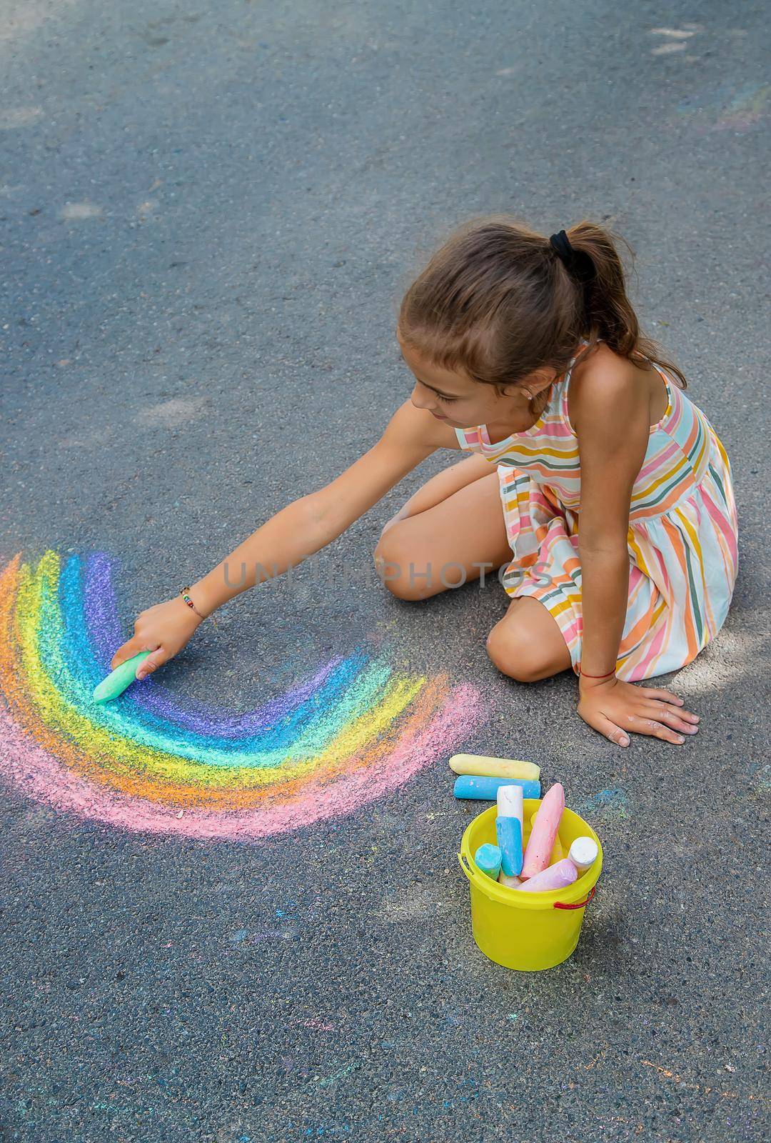 Children paint a rainbow on the asphalt. Selective focus. by yanadjana