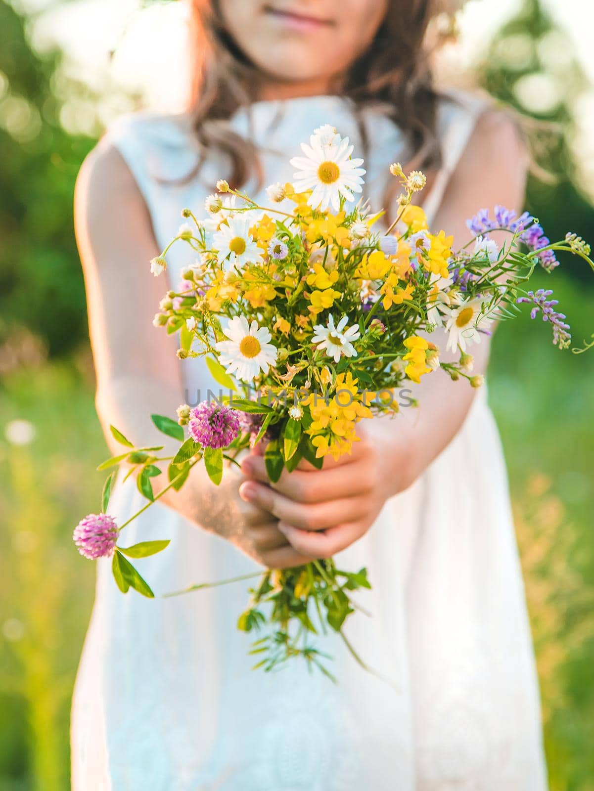 Child girl with wildflowers in summer. Selective focus. Nature.