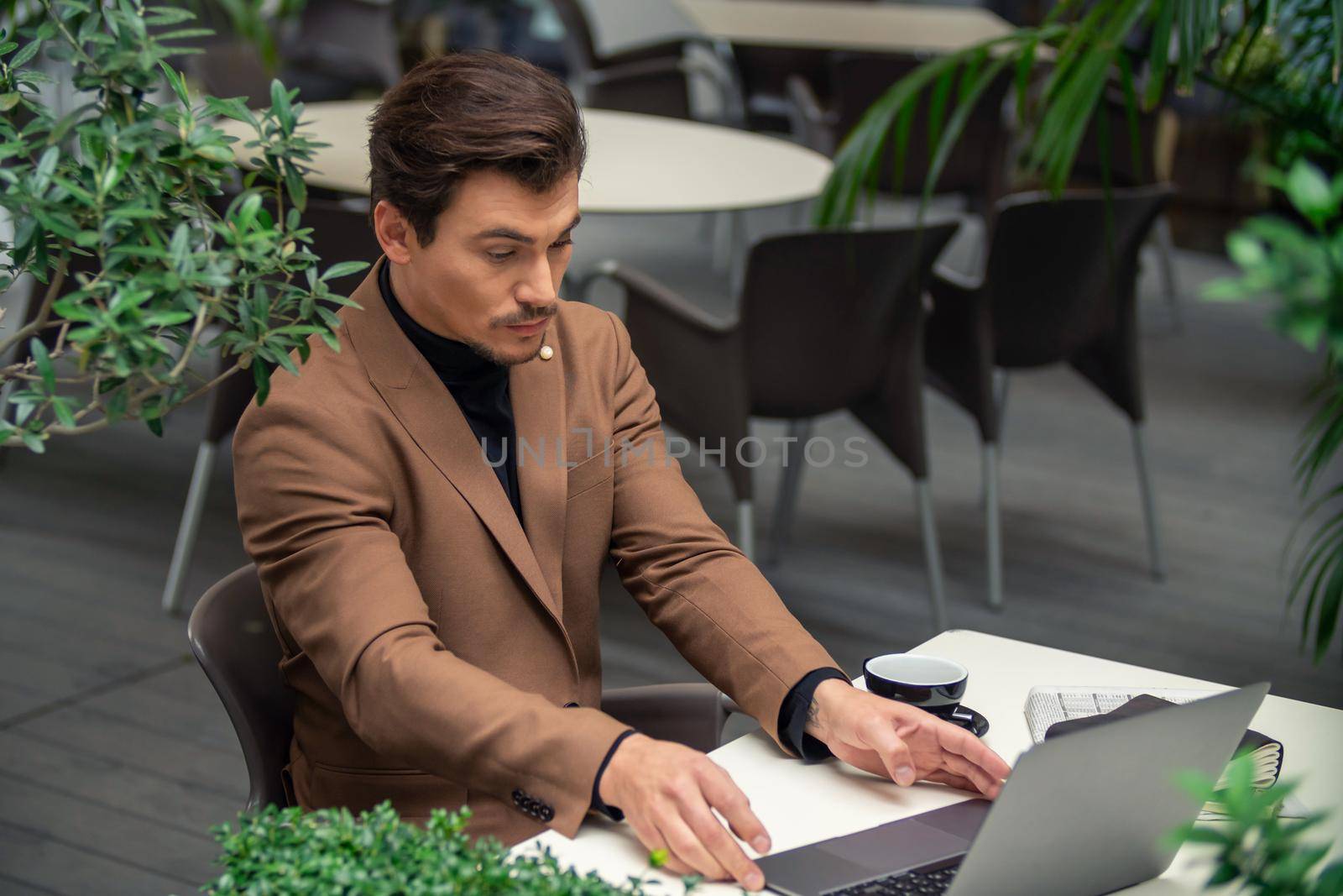businessman sitting at a table in a cafe with a laptop