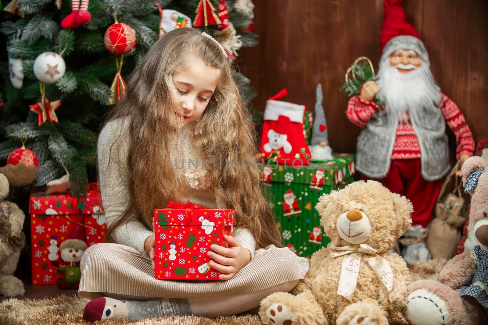 Girl with a gift box in her hands on the background of a christmas tree