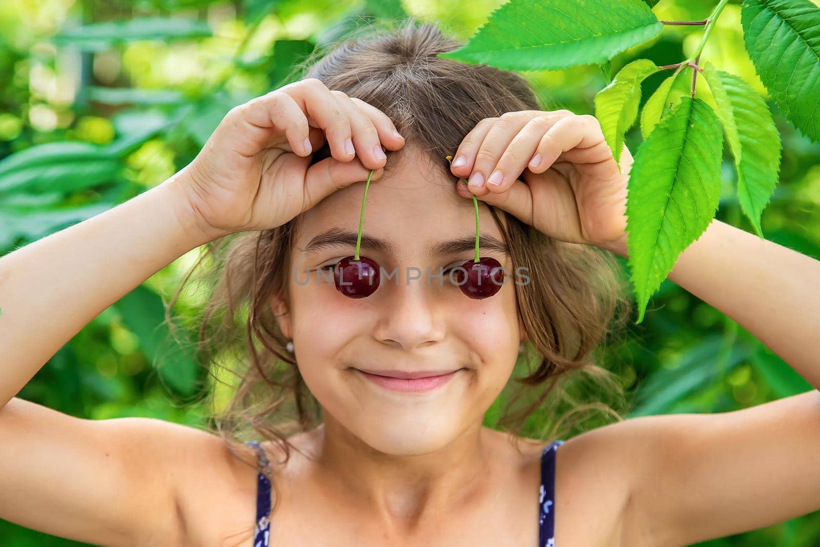 The child eats cherries in the garden. Selective focus. Food.