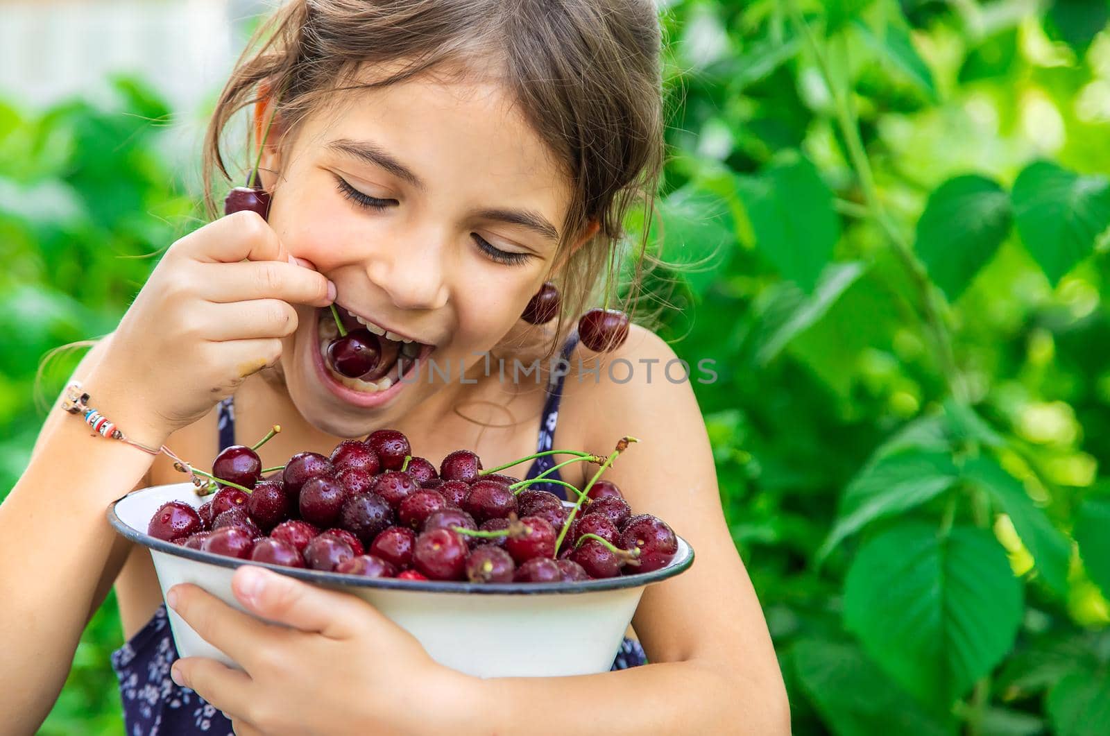 The child eats cherries in the garden. Selective focus. Food.