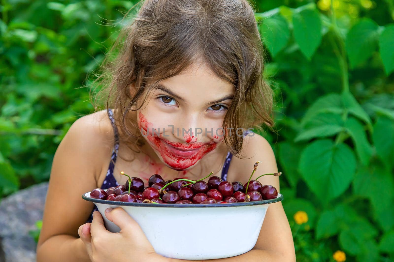 The child eats cherries in the garden. Selective focus. Food.