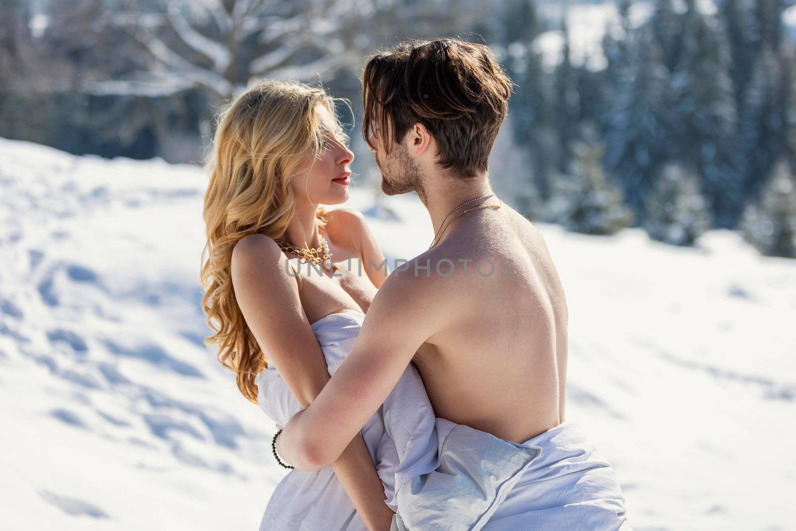 couple in blankets on the background of a snowy forest