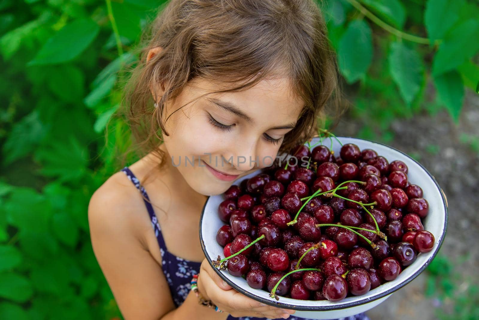 The child eats cherries in the garden. Selective focus. Food.