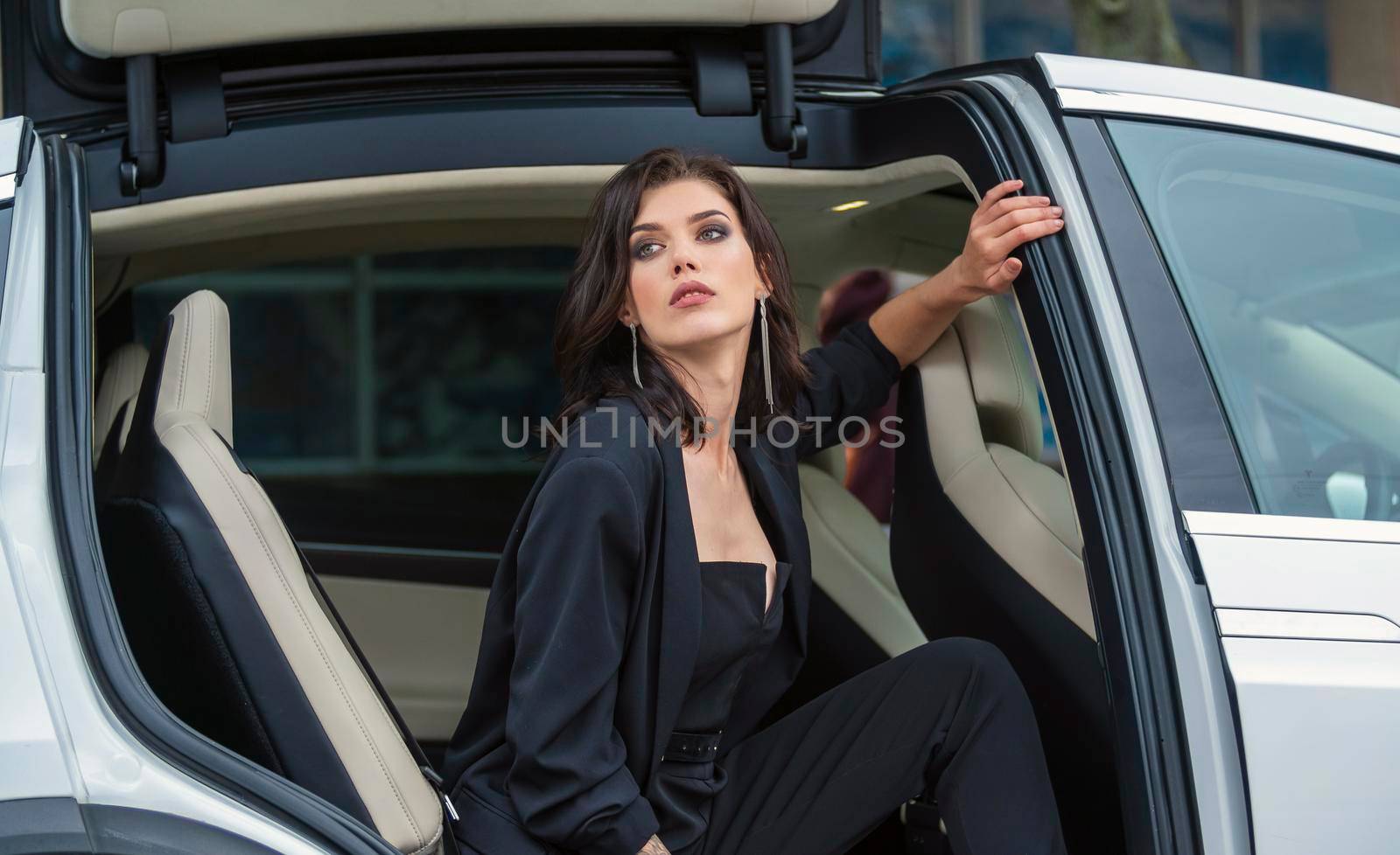a woman in a business suit sits in the back seat of a car