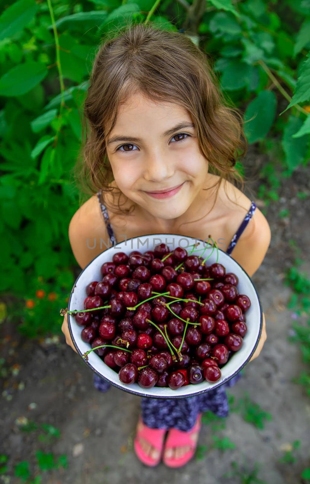 The child eats cherries in the garden. Selective focus. Food.