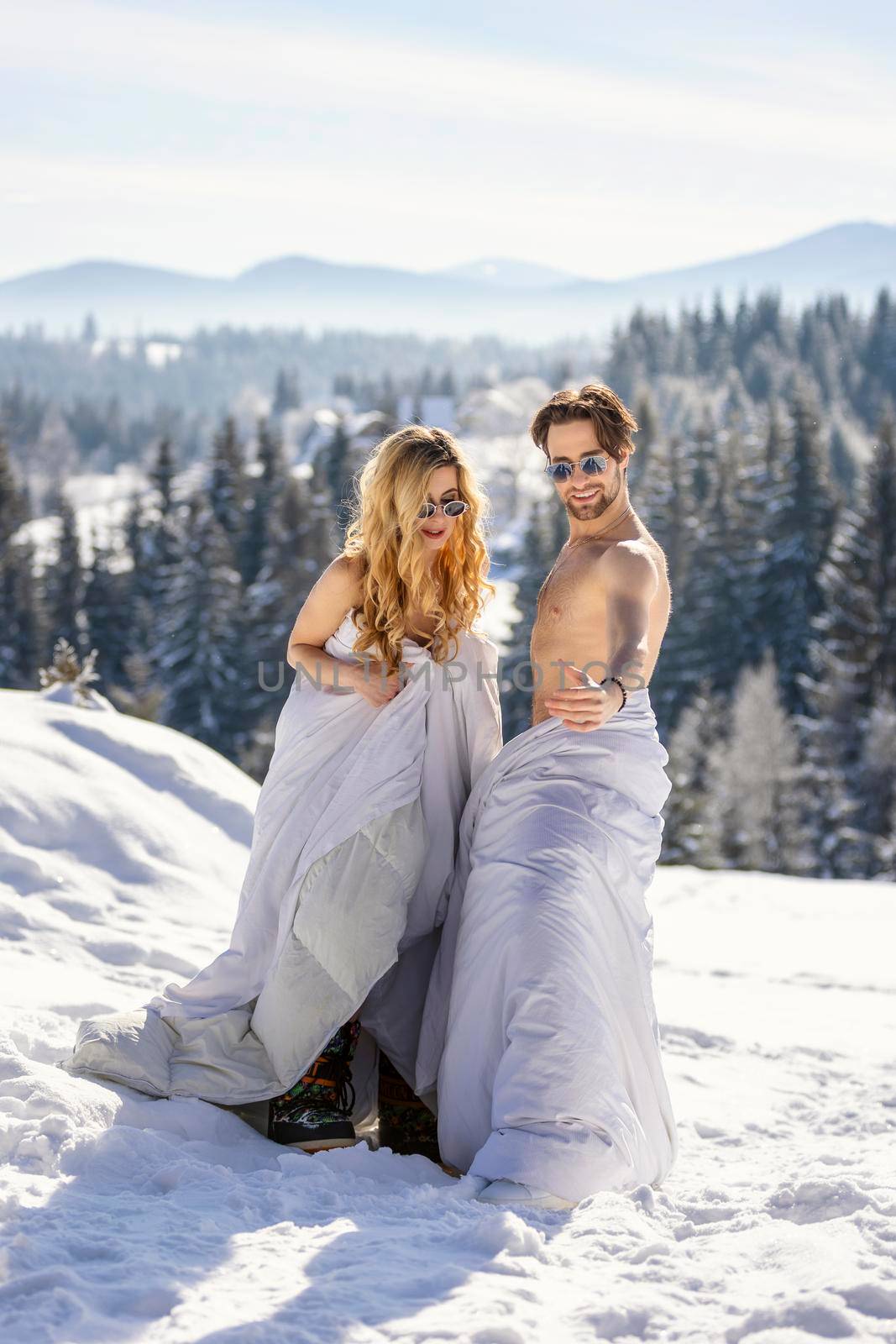 couple in blankets in winter on the background of forest and mountains
