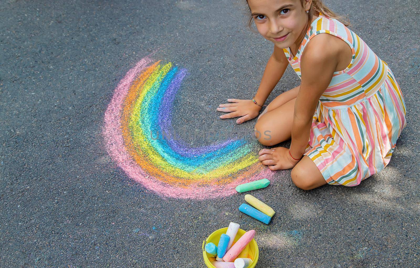 Children paint a rainbow on the asphalt. Selective focus. by yanadjana